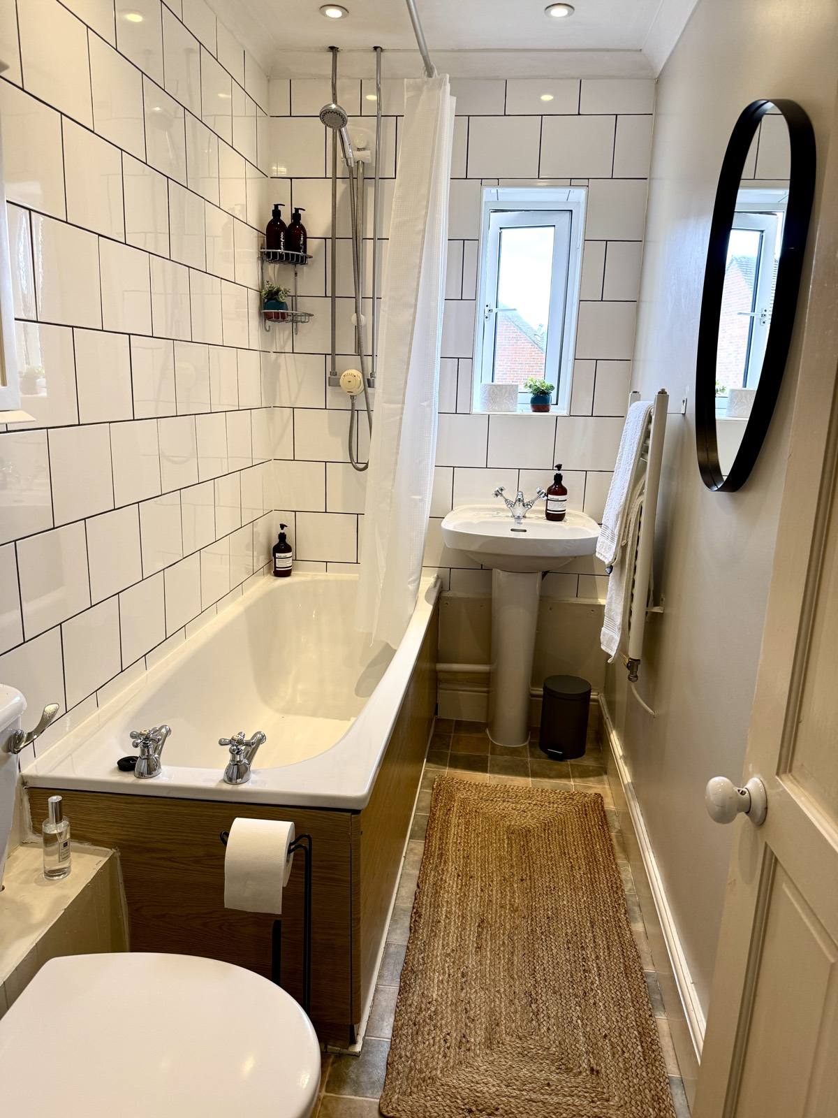Bathroom with a bath, overhead shower and white metro tiles