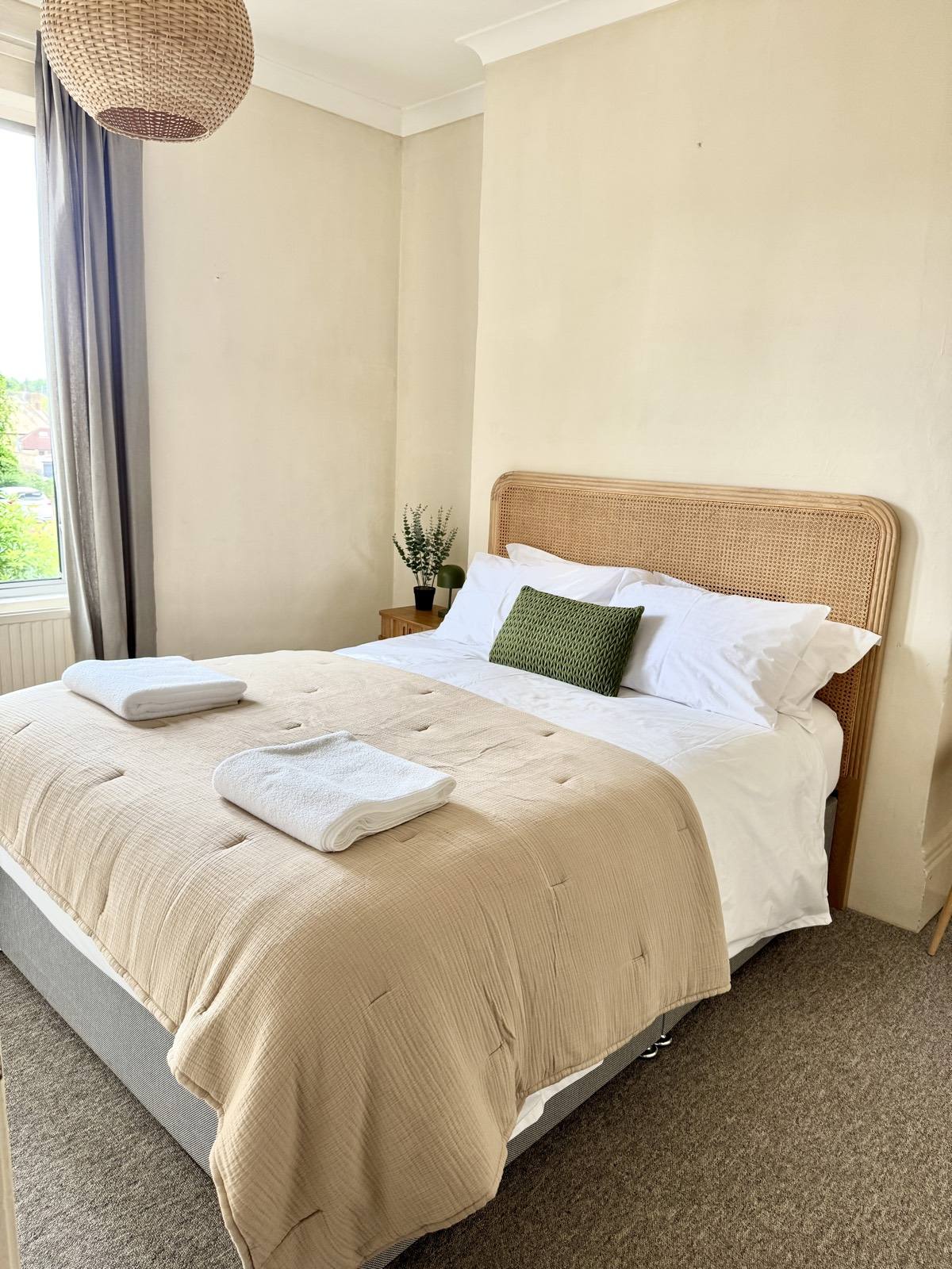 Double bedroom with a cane headboard and crisp white linen