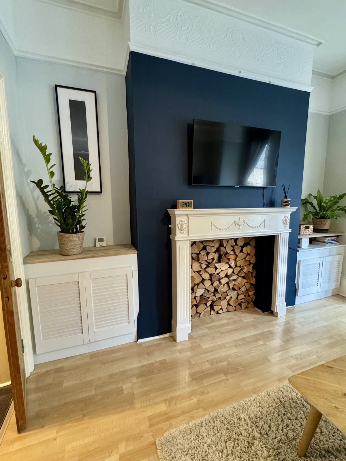 Living room feature fireplace with neat log store and wall-mounted TV